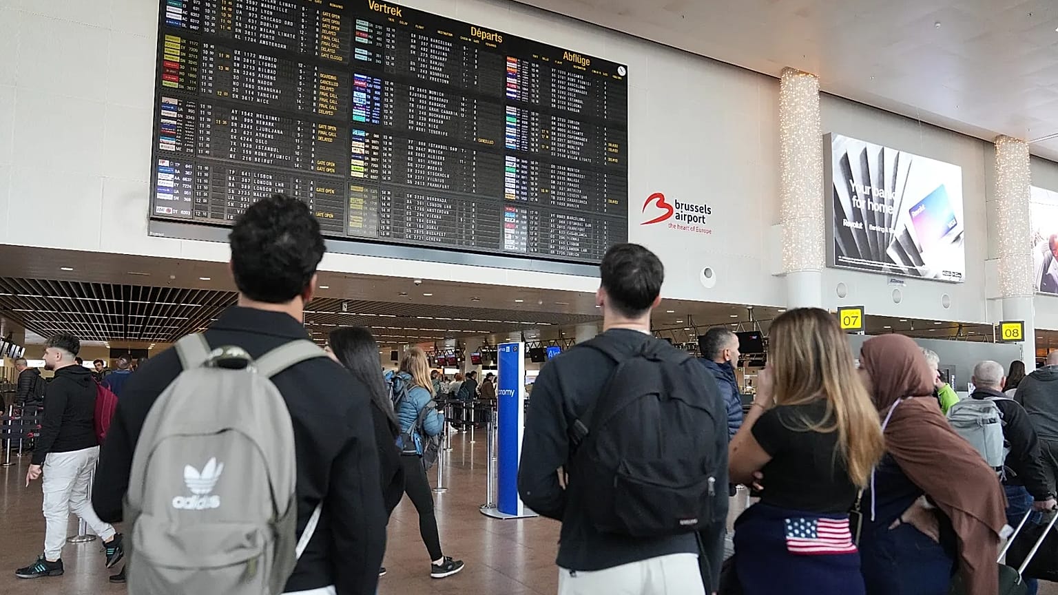 Passengers look at a departure board after several cancellations and delays due to reported overnight drone activity over Brussels International Airport, 5 November, 2025