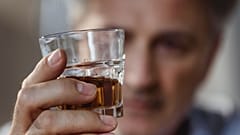 Ein älterer Mann hält eine Flasche Schnaps.