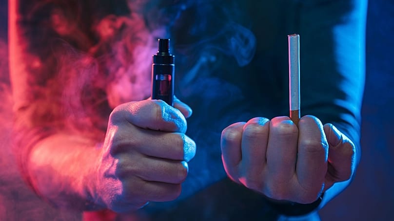 رجل يمسك سيجارة تقليدية وأخرى إلكترونية