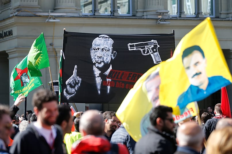 A banner reads; 'Kill Erdoğan with his own weapons' as protesters march during a demonstration against the Turkish president in Bern, 25 March, 2017 