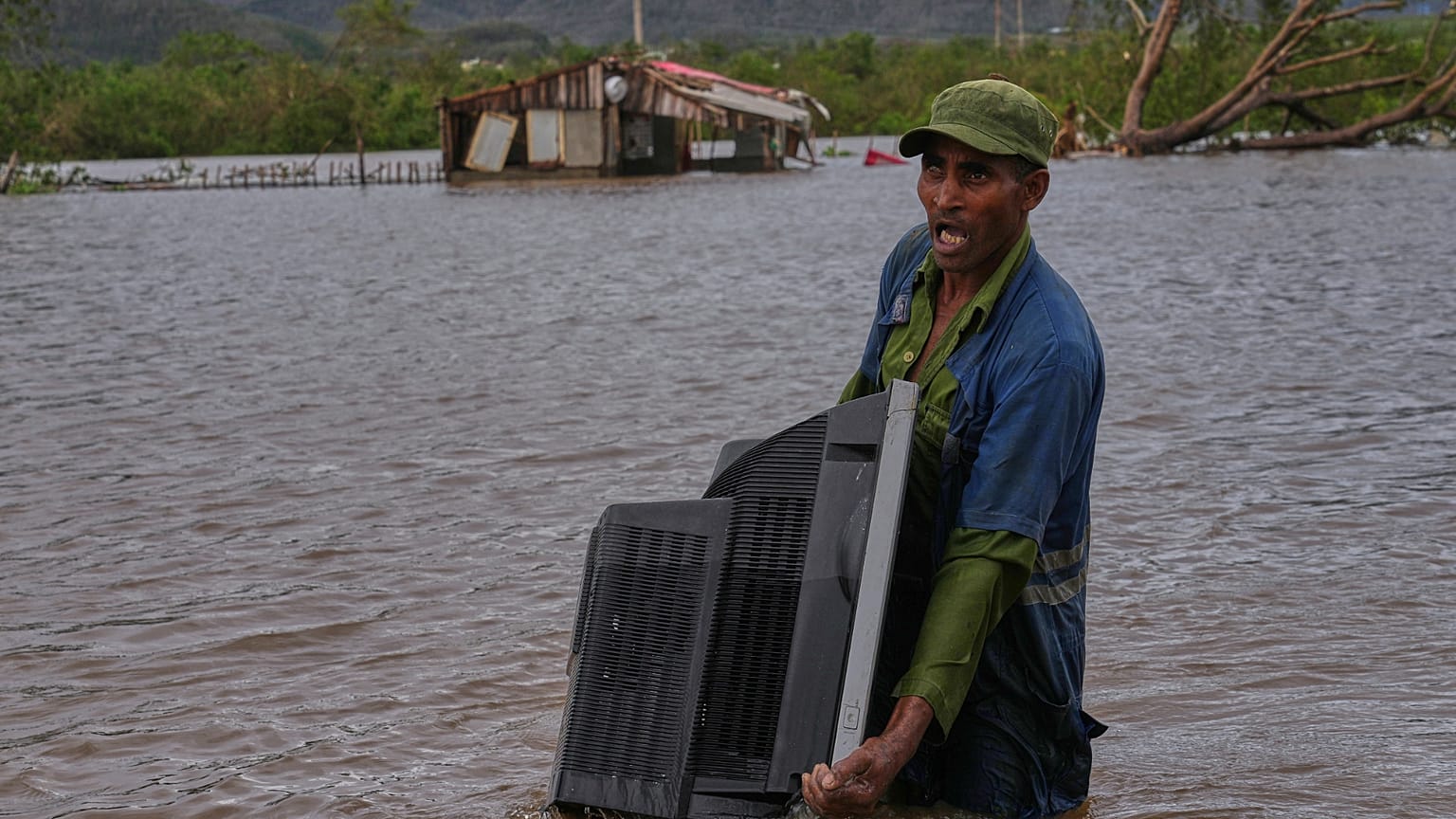 ARCHIVO - Un hombre vadea una zona inundada cargando un televisor de su casa tras el paso del huracán Melissa, en Santiago de Cuba, 29 de octubre de 2025.