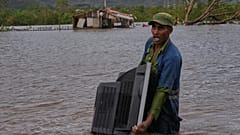 ARCHIVO - Un hombre vadea una zona inundada cargando un televisor de su casa tras el paso del huracán Melissa, en Santiago de Cuba, 29 de octubre de 2025.