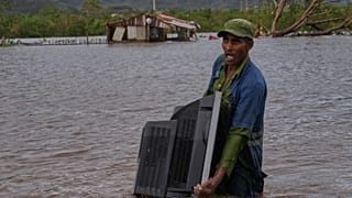 ARCHIVO - Un hombre vadea una zona inundada cargando un televisor de su casa tras el paso del huracán Melissa, en Santiago de Cuba, 29 de octubre de 2025.