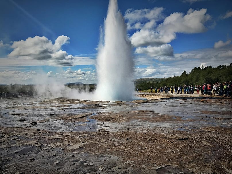 People watching a geyser eruption in Iceland