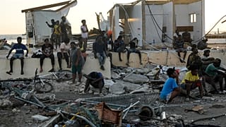 People gather among debris near a bridge in Black River, Jamaica, Oct. 30, 2025, in the aftermath of Hurricane Melissa. 