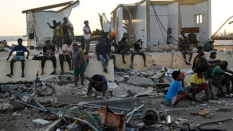 People gather among debris near a bridge in Black River, Jamaica, Oct. 30, 2025, in the aftermath of Hurricane Melissa. 