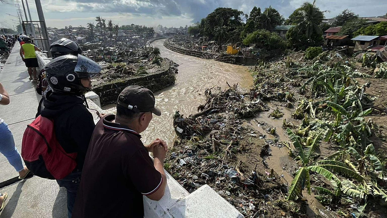 رجال ينظرون إلى المنازل المتضررة بعد أن تسبب إعصار كالمايجي في دمار المجتمعات على طول نهر مانانجا في مدينة تاليساي، مقاطعة سيبو في الفلبين