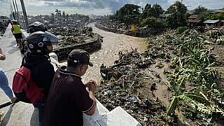 رجال ينظرون إلى المنازل المتضررة بعد أن تسبب إعصار كالمايجي في دمار المجتمعات على طول نهر مانانجا في مدينة تاليساي، مقاطعة سيبو في الفلبين