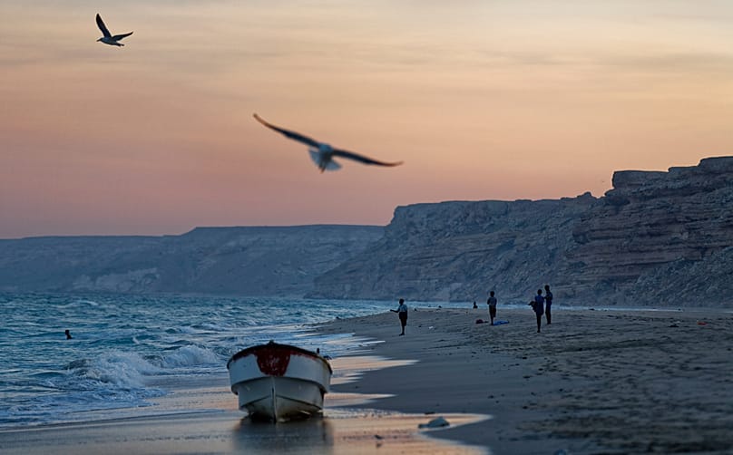 FILE - Fishermen stand on the Indian Ocean beach at dusk in the former pirate village of Eyl, in Somalia's semiautonomous state of Puntland, Somalia, Monday March 6 2017