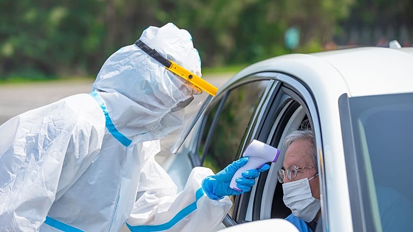 عامل صحي يفحص رجلًا داخل سيارته ضمن إجراءات الوقاية من كوفيد-19.