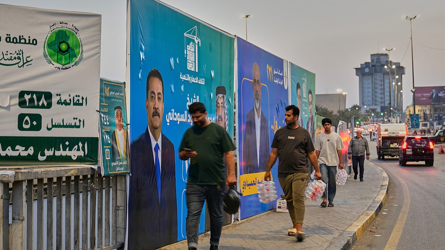 سكان محلّيون يمرّون قرب لافتة تدعو إلى مقاطعة الانتخابات في مدينة الصدر بضواحي بغداد، 22 أكتوبر 2025.