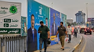 سكان محلّيون يمرّون قرب لافتة تدعو إلى مقاطعة الانتخابات في مدينة الصدر بضواحي بغداد، 22 أكتوبر 2025.