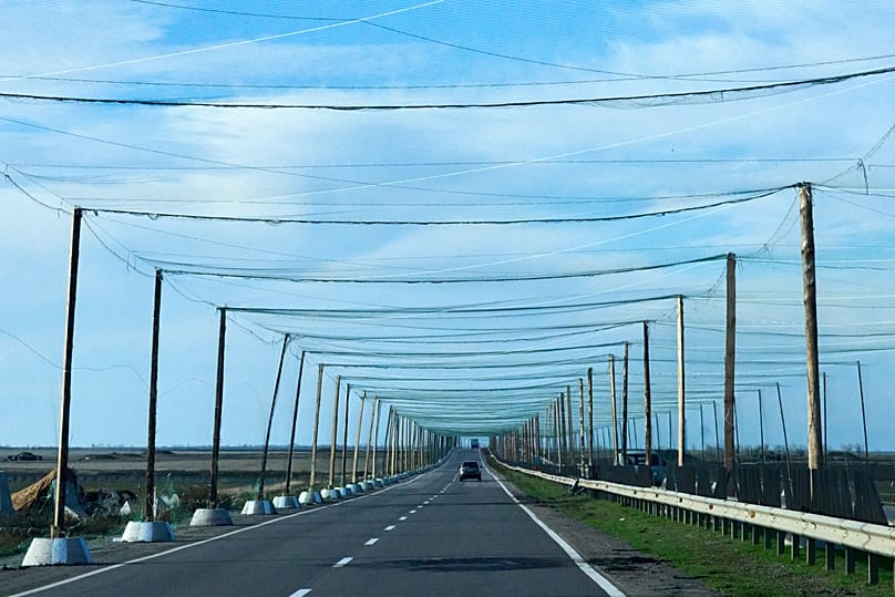 Cars drive on the road covered with an anti-FPV-drone net at the approaches to the frontline city of Kherson, Southern Ukraine, Monday, Nov. 3, 2025