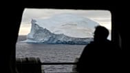 أحد ركاب السفينة البحرية التشيلية "أكوليس" ينظر إلى جبل جليدي في مضيق برانسفيلد، جزر شيتلاند الجنوبية، أنتاركتيكا