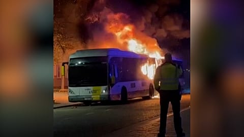 Un policier se tient devant le bus en flammes transportant des supporters du FC Barcelone, Bruges, Belgique, 05.11.2025