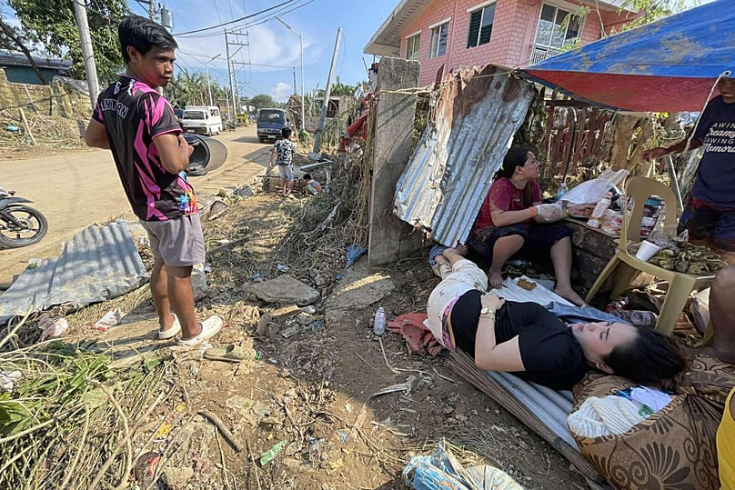 A family rest outside their flood damaged home caused by Typhoon Kalmaegi, in Liloan, Cebu province, central Philippines on Thursday, Nov. 6, 2025
