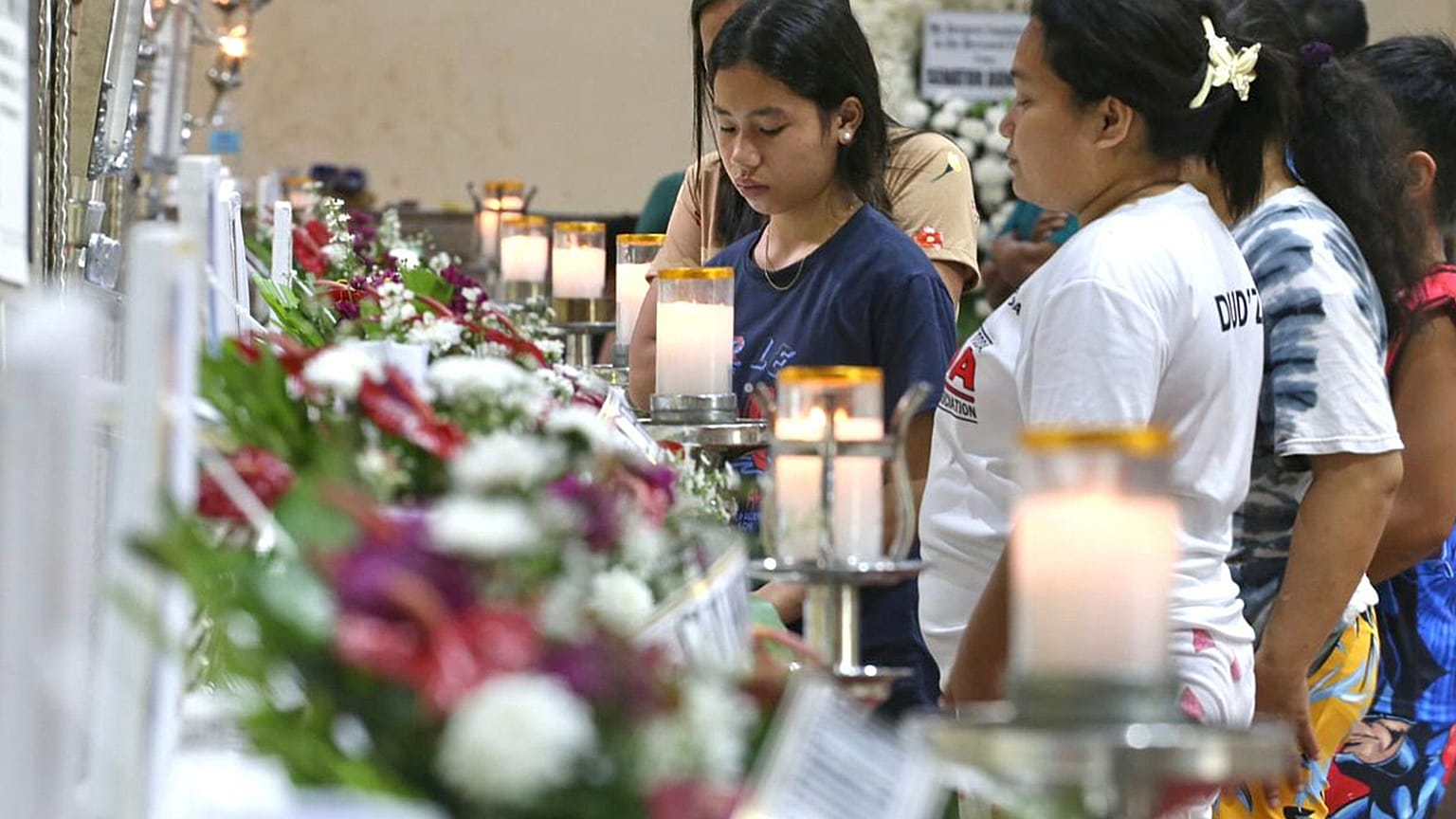Relatives and friends stand near coffins in Bacayan, Cebu province