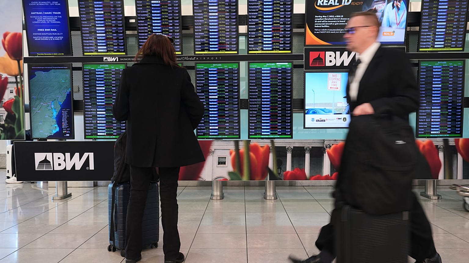 يتفقد أحد المسافرين لوحة معلومات الرحلات بينما يمر آخرون عبر صالة المطار في مطار بالتيمور/واشنطن الدولي ثورغود مارشال في بالتيمور، يوم الخميس 6 نوفمبر 2025. 