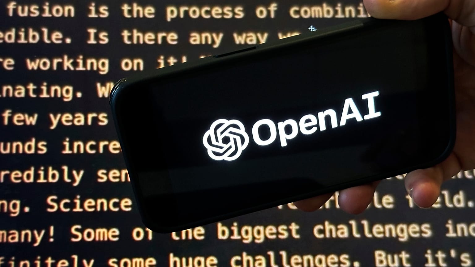 El logotipo de OpenAI aparece en un móvil frente a una pantalla que muestra parte del sitio web de la empresa, en una foto del 21 de noviembre de 2023 en Nueva York.