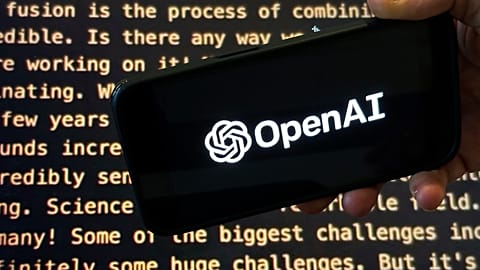 The OpenAI logo appears on a mobile phone in front of a screen showing part of the company website in this photo taken on Nov. 21, 2023 in New York.
