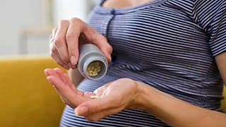 A pregnant woman prepares to take medication.