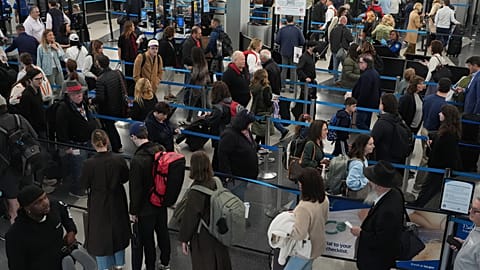 Travelers wait at a security checkpoint at O'Hare International Airport in Chicago, Friday, Nov. 7