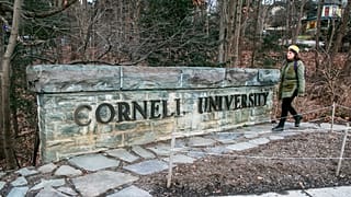 FILE - A woman walks by a Cornell University sign on the Ivy League school's campus in Ithaca, New York, Jan. 14, 2022