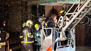 Firefighters evacuate a resident following a Russian rocket attack that hit a multi-storey apartment building in Dnipro, Ukraine, Saturday, Nov. 8, 2025