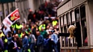 ARQUIVO (25.11.2014): Uma mulher tira fotografias de dentro de um elétrico enquanto as pessoas marcham durante um protesto da CGTP em Lisboa