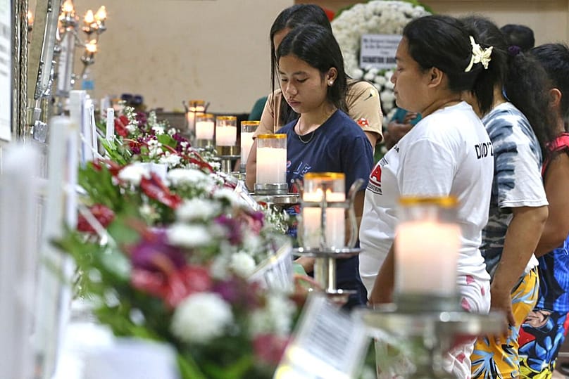 Relatives and friends stand near coffins in Bacayan, Cebu province, Philippines on Friday Nov. 7, 2025 after Typhoon Kalmaegi devastated the province and claimed lives