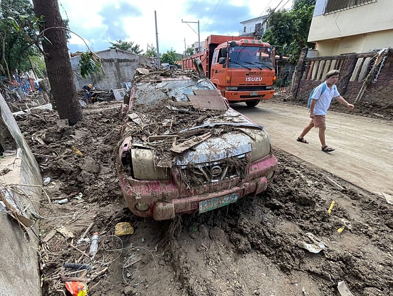 A man passes by a debris laden car as residents return to their flood damaged homes in Bacayan, Cebu province, central Philippines, after Typhoon Kalmaegi, Friday Nov. 7, 2025