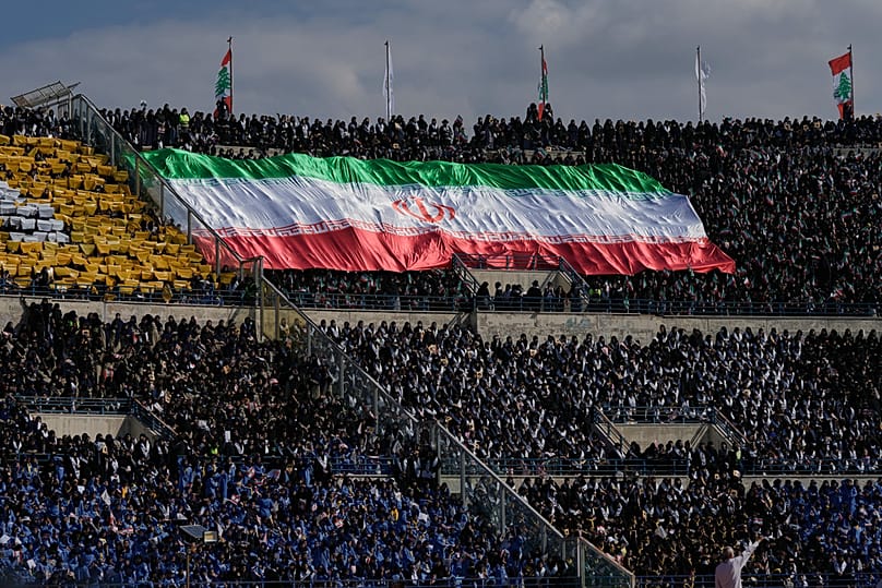 آلاف من أعضاء كشافة المهدي التابعة لحزب الله يرفعون علمًا إيرانيًا ضخمًا خلال احتفال في ملعب المدينة الرياضية في بيروت، لبنان، الأحد 12 أكتوبر/تشرين الأول 2025.