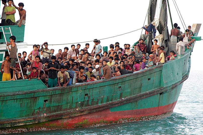  في هذه الصورة الأرشيفية الملتقطة في 20 مايو/أيار 2015، يجلس مهاجرون، بينهم مسلمو الروهينجا، على متن قاربهم قبالة شرق آتشيه بإندونيسيا.
