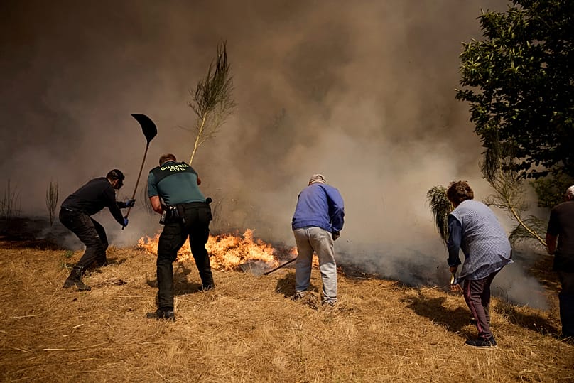 Residents battle a wildfire advancing toward Rebordondo village, near Ourense, in northwestern Spain, Aug. 18, 2025.