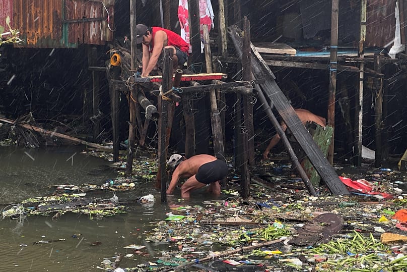 Los residentes reparan sus casas durante las lluvias provocadas por el tifón Fung-wong en una aldea costera el lunes 10 de noviembre de 2025, en Navotas, Filipinas. 