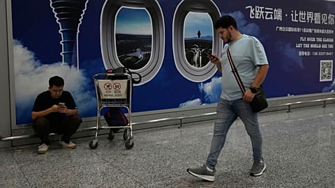 A foreigner walks past a sign board for the Baiyun airport in Guangzhou in southern China's Guangdong province on Nov. 6, 2025.