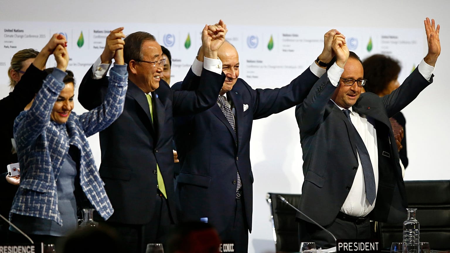 François Hollande, à droite, Laurent Fabius, deuxième à droite, Christiana Figueres, à gauche, et Ban Ki-moon lèvent les mains pour célébrer la fin de la COP21, en 2015.