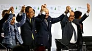 François Hollande, a destra, Laurent Fabius, secondo da destra, Christiana Figueres, a sinistra, e Ban Ki-moon alzano le mani in segno di gioia alla fine della COP21 nel 2015.