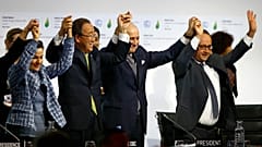 François Hollande (rechts), Laurent Fabius (zweiter von rechts), Christiana Figueres (links) und Ban Ki-moon heben am Ende der COP21 2015 jubelnd die Hände.