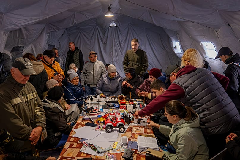 People charge their phones in a heated tent in Chernihiv, 21 October, 2025