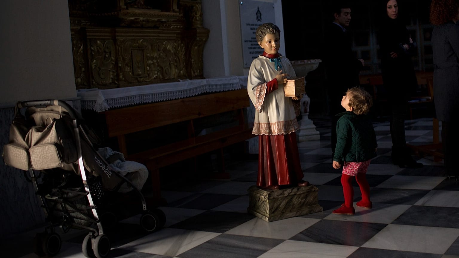 Un niño mira a una figura que representa a un monaguillo pidiendo donaciones dentro de una iglesia en Medina Sidonia, Cádiz, España, el 29 de marzo de 2013.