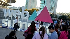 Teilnehmende posieren für Fotos vor dem Logo der Technologiekonferenz Web Summit außerhalb des Veranstaltungsortes in Lissabon. Montag, 13. November 2023.