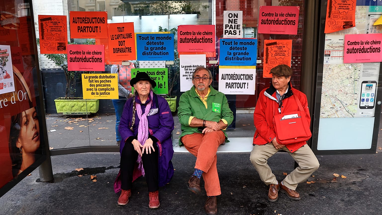 People sit in a shelter as they gather with others for a protest march against the high cost of living and climate inaction in Pari