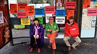 People sit in a shelter as they gather with others for a protest march against the high cost of living and climate inaction in Pari