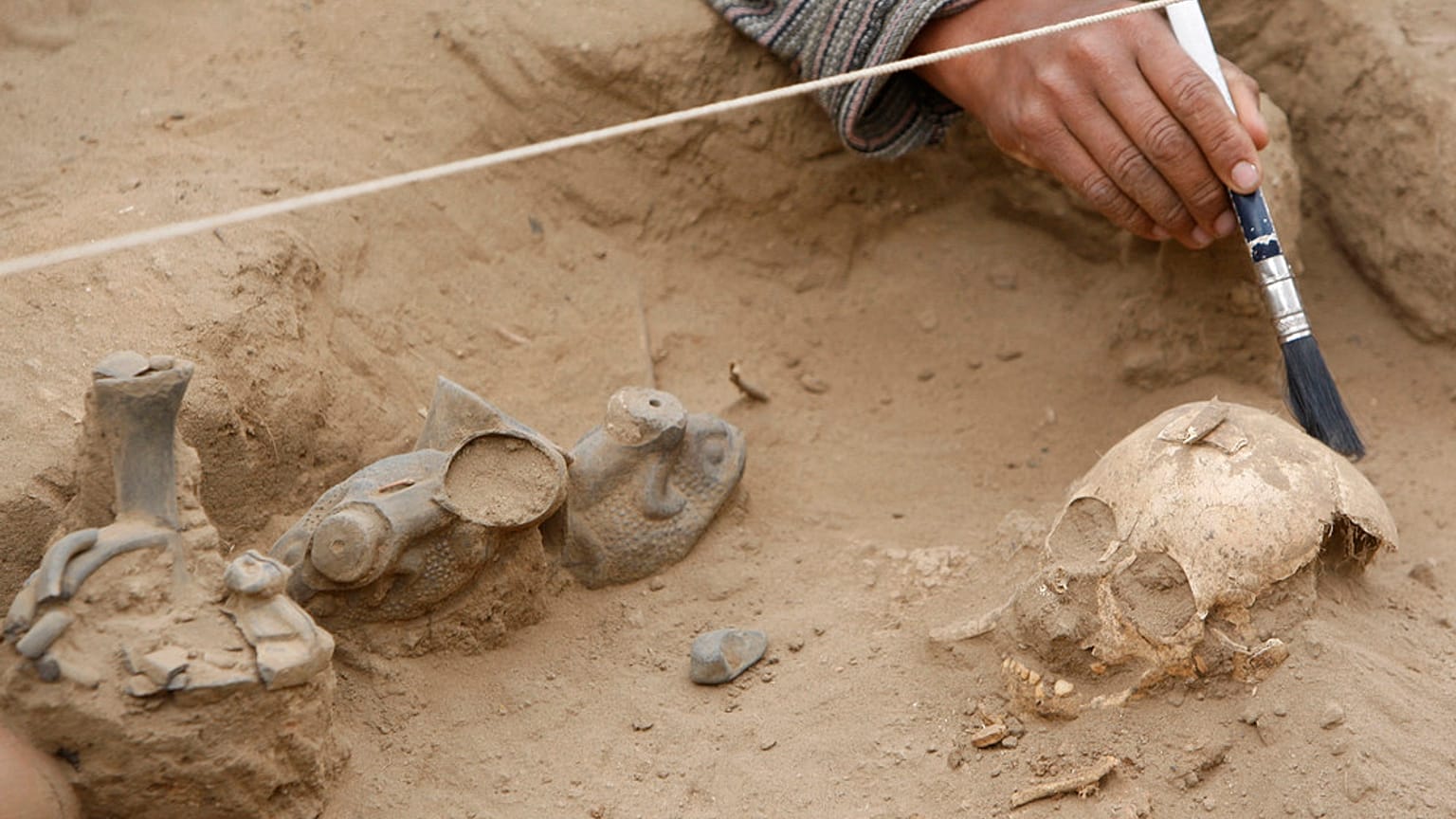 رجل يعمل على رفات طفل في مجمع بوسكيه دي بوماك الأثري في لامباييك،