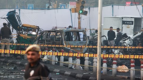 A policeman stands guard as investigators examine the site of Monday's car explosion near the historic Red Fort, in New Delhi, India, Tuesday, Nov. 11, 2025.
