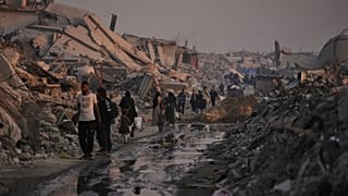 فلسطينيون في قطاع غزة يمشون بين الركام