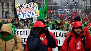 Sendika çalışanları Brüksel'de düzenlenen bir gösteri sırasında 'maaşlar ve emekli maaşları artırılsın' yazılı bir pankartla yürüyor, 16 Aralık 2022. 