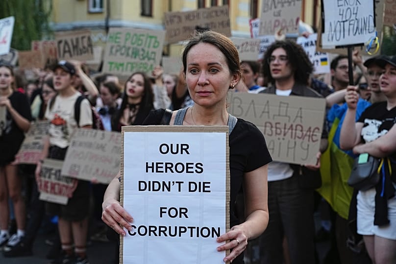 Uma mulher segura uma faixa durante um protesto contra uma lei que visa as instituições anti-corrupção no centro de Kiev, Ucrânia, quarta-feira, 23 de julho de 2025.