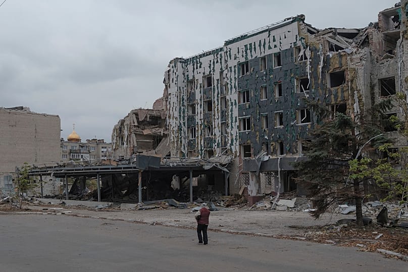 FILE: A woman walks in front of Druzhba hotel destroyed by Russian airstrikes in Pokrovsk, Monday, Nov. 11, 2024. 